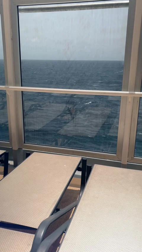 Calm ocean view through large window with sun loungers on the deck of a cruise Stock Footage 308250365