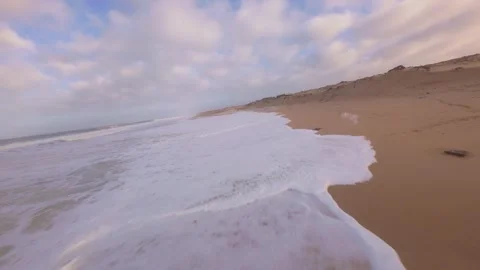 Calm ocean washes over sandy shores during peaceful sunset Stock Footage 345149828