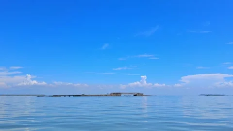 Calm ocean water with a distant pier under blue sky Vídeo Stock 331805739
