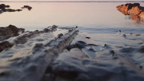 Calm ocean water flows gently over textured rocky coastal shore Stock Footage 337410326