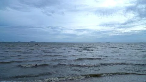 Calm ocean water with small waves under cloudy sky Stock Photos