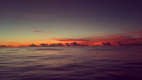 Calm ocean waters reflecting vibrant colors of a stunning sunset against a .. Stock Footage 338281728