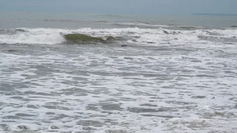 Calm ocean waves breaking on a sandy shore under a cloudy sky. Stock Footage 329738267