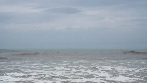 Calm ocean waves breaking on a sandy shore under a cloudy sky. Stock Footage 329782982