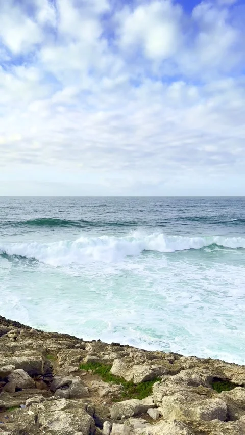Calm ocean waves crash against rocky shoreline at a coastal location Stock Footage 317986035