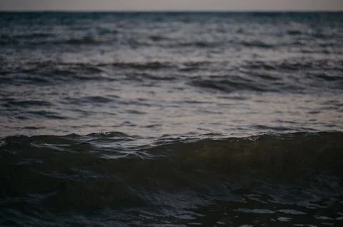 Calm ocean waves at dusk with soft reflections on the water surface Stock Photos