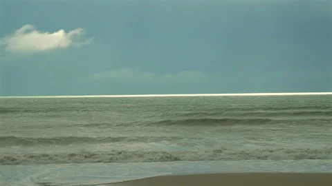 Calm ocean waves gently lapping sandy shore under clear blue sky with Stock Footage 282082949