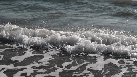 The Calm Ocean Waves Gently Lapping Against the Shore with Sunlit Foam Sparkling Stock Footage 312524328