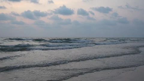 Calm ocean waves gently rolling onto sandy beach at dusk Video stock 306739418