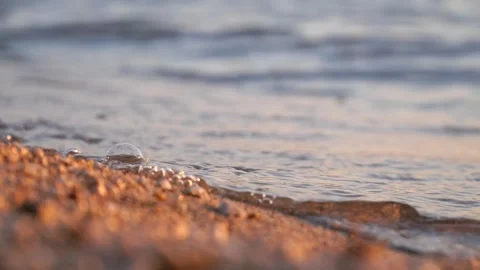 Calm ocean waves gently washing onto the warm sandy shoreline Stock Footage 337417908