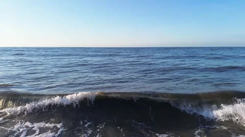 Calm ocean waves moving slowly under a clear blue sky, Gentle blue waves flowing Stock Footage 327097611