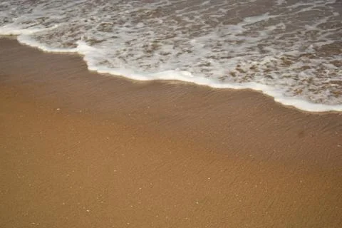 Calm Ocean Waves Reaching a Pristine Sandy Shoreline at the Coast 库存照片