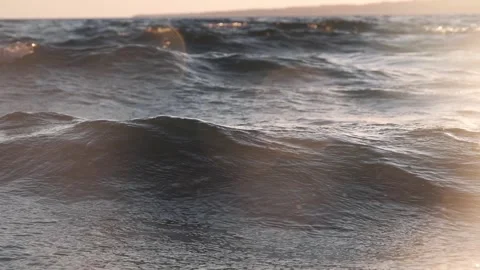 Calm ocean waves rippling gently under a warm evening sunset Stock Footage 342423575