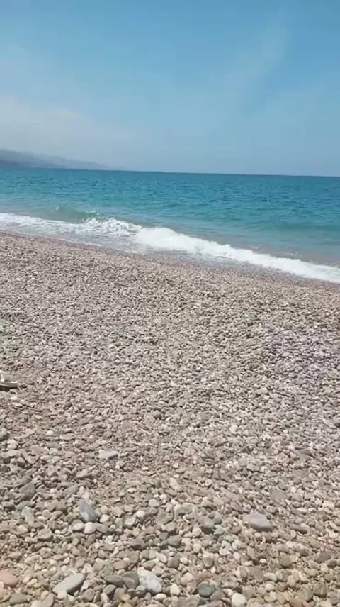 Calm Ocean Waves Rolling on Pebble Beach on Sunny Day Stock Footage 335478343