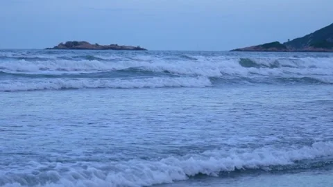 Calm ocean waves rolling onto a sandy beach at twilight Stock Footage 347049500
