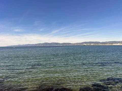 Calm Ocean Waves Sparkling Under a Bright Blue Sky at Midday Stock Photos