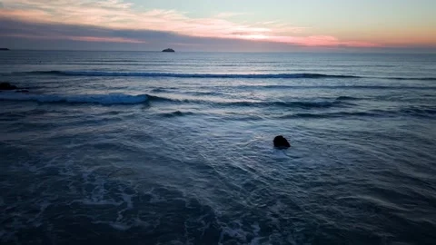Calm ocean waves at sunset with island on horizon aerial footage Stock Footage 331193802