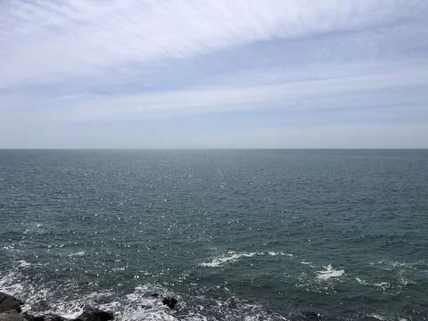 Calm Ocean Waves Under a Clear Sky on a Sunny Day at the Shore Stock Photos