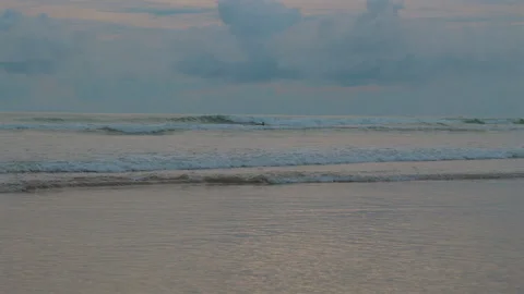 Calm ocean waves under cloudy sky during sunset with serene water Stockbeeldmateriaal 282083730