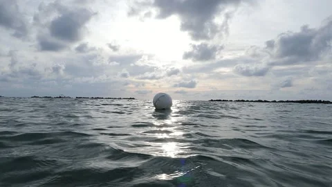 Calm ocean waves under a cloudy sky with a buoy in the foreground Stock Footage 327138025