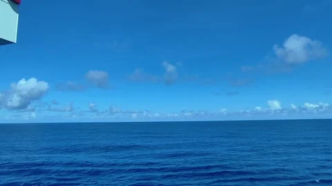 Calm ocean waves under a vast blue sky from a moving ship clip Stock Footage 344369078