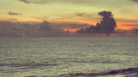 Calm ocean waves under a vibrant sunset with dramatic clouds on the horizon Stock Footage 338281462
