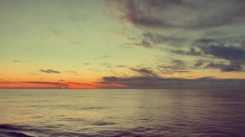 Calm ocean waves under a vibrant sunset sky with various clouds and subtle .. Stock Footage 338281973
