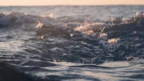 Calm ocean waves washing over wet dark rocks at dusk Stock Footage 337419433