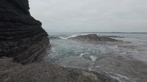 Calm ocean waves washing over dark rock shelf on irish coast Stock Footage 340463568