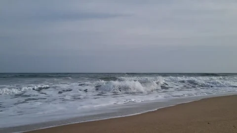 Calm overcast seascape with rolling waves approaching the quiet shoreline Stock Footage 322124653