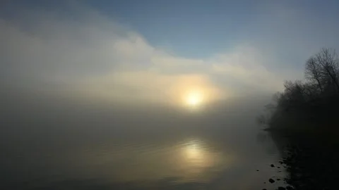 Calm peaceful setting at a quiet lake as the sun rises through the fog.  Stock Footage 255148742