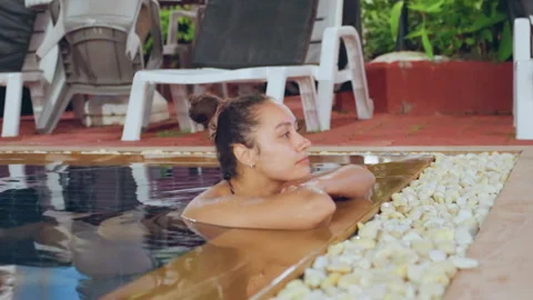 Calm Polynesian lady resting by poolside. Relaxed Polynesian woman reclining Stock Footage 332941349
