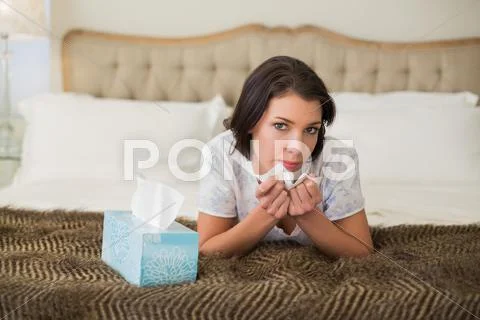 Calm pretty brown haired woman sneezing in a tissue Stock Photos