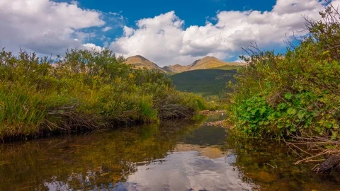 Calm Reflection still stream rising into glorious mountain range Time Lapse 4K Stock Footage 129354634