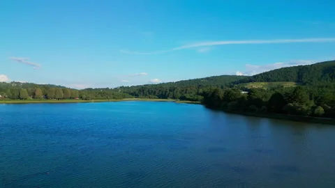 Calm reservoir stretching between forested hills under a clear blue sky Stock Footage 346014751