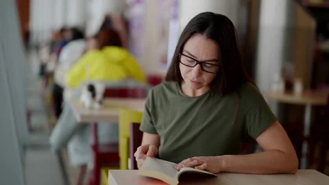 Calm rest in cafe in dinner time, adult woman is reading book, sitting at table Stock-Footage 169701391