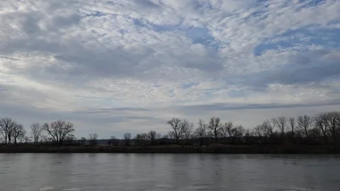 Calm river beneath expansive cloud-filled sky Stock Footage 331764426
