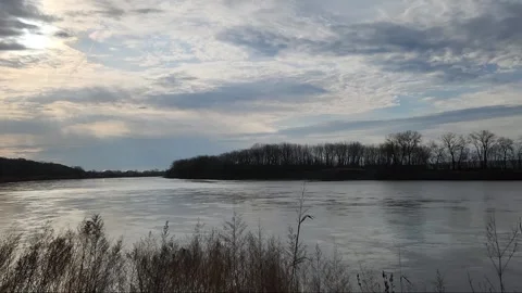 Calm river beneath textured sky with soft cloud movement Stock Footage 331765118