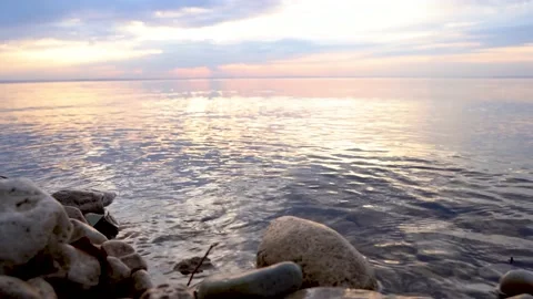 A calm river or lake at sunset. Beautiful sky and focus on the rocks Stock Footage 154583343