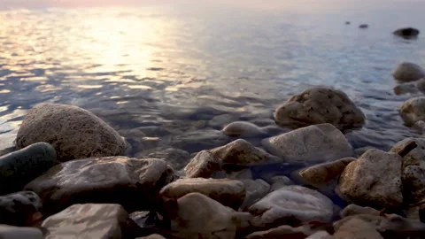 A calm river or lake at sunset. Beautiful sky and focus on the rocks Stock Footage 154583482
