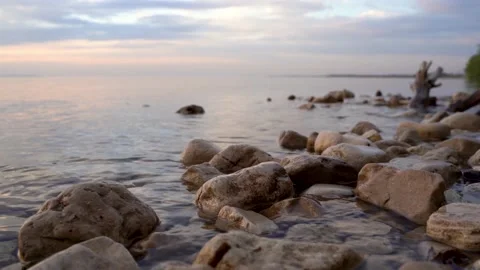 A calm river or lake at sunset. Beautiful sky and focus on the rocks Stock Footage 154583592