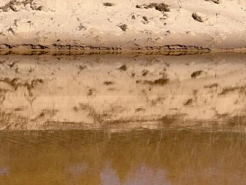Calm River Reflection on Sandy Bank Background Texture Foto stock