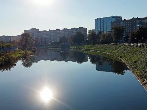 Calm River with Sun Reflection and City Skyline – Urban Waterfront Landscape Stock Photos