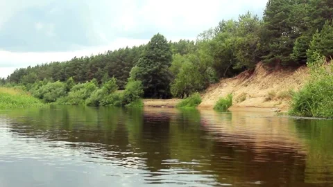 Calm river water flows past green trees and banks Video stock 333835033