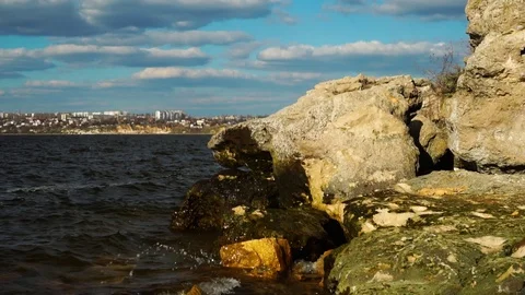 Calm river waves splashing on rock stone beach in time lapse skyline panorama of Stock Footage 107333295