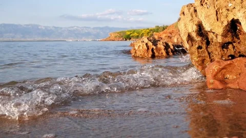 Calm Rocky Shoreline With Small Waves Lapping Against Red Cliffs Stock Footage 337406562