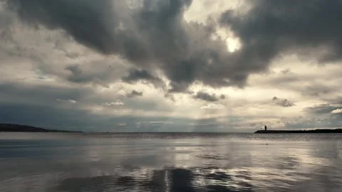 Calm Sea and Distant Lighthouse Under Dramatic Dark Cloudy Sky, Büyükçekmece Vídeo Stock 323820683