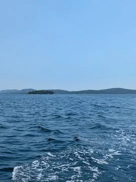 Calm sea with distant tree covered islands under clear blue sky and soft ho.. Stock Photos