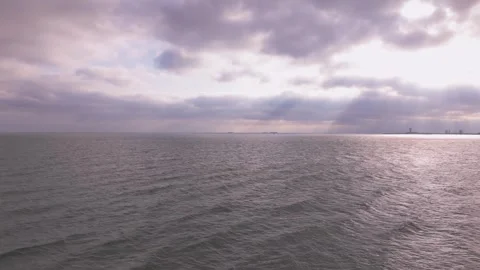 Calm sea horizon with dramatic cloudy sky and sun rays breaking through clouds Stock Footage 315515411