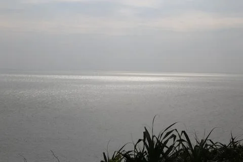 The calm sea surface, the distant horizon of flat water and sky, is reflect.. Stock Photos